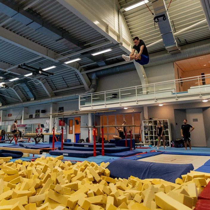 Indoor sports facility with gymnasts and a foam pit