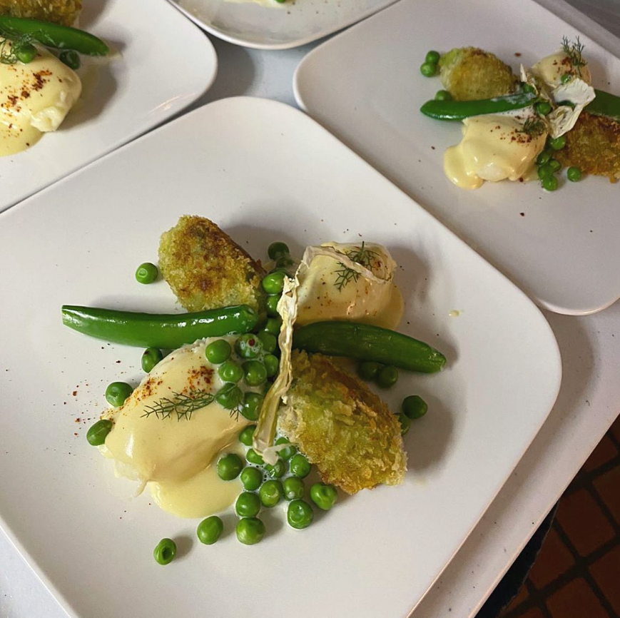 Plated dish with green beans, peas, and a creamy sauce on a white plate.