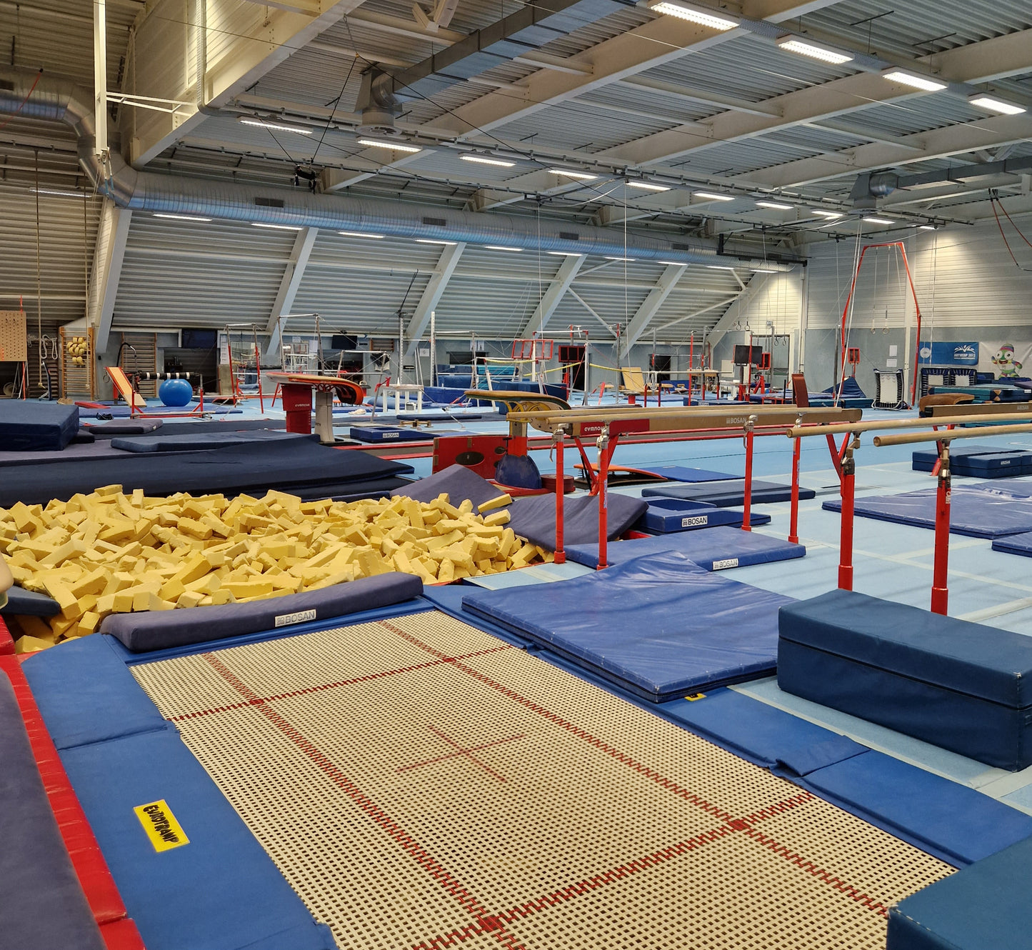 Gymnasium with trampolines, foam pits, and various sports equipment.