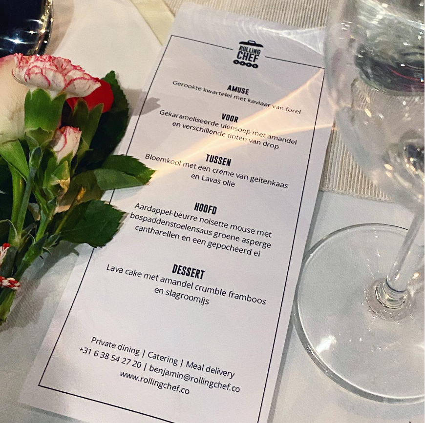 Dinner menu with flowers and a glass of water on a table