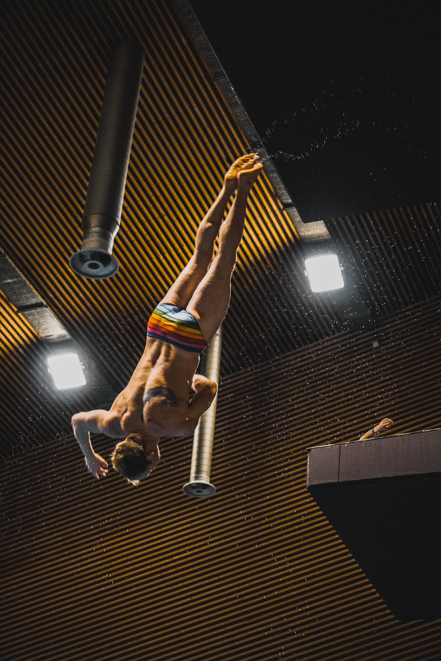 Person diving from a diving board at with water splashing around above a swimming pool