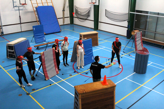 Group of people practicing with archery tag in a gymnasium