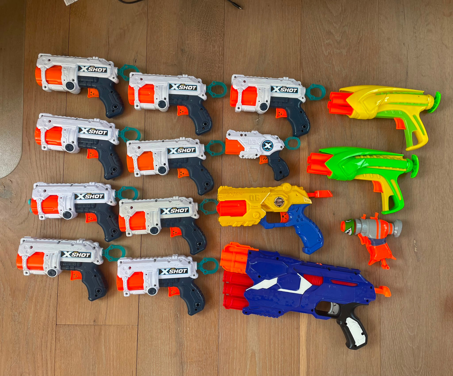 Collection of toy hand nerf guns on a wooden floor